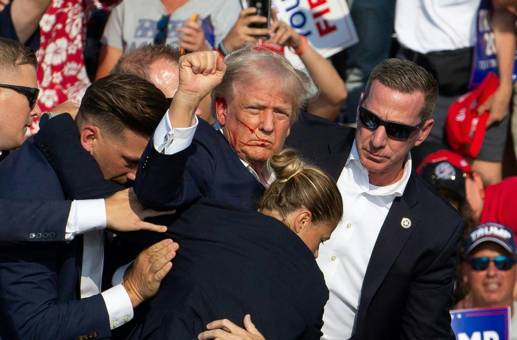 Donald Trump with blood on his face being accompanied by secret service agents.