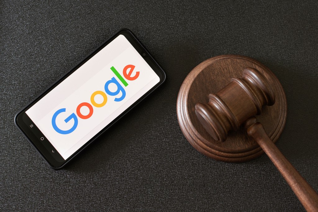 Smartphone displaying Google logo next to a glass of a judge.